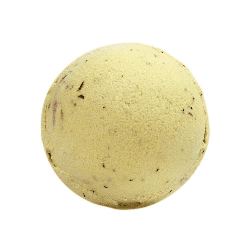Yellow bath bomb with specks on a white background