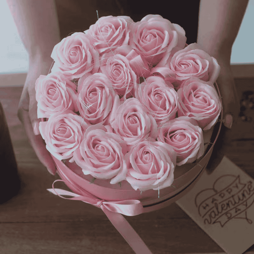 Bouquet of pink soap roses in a box with a 'Happy Valentine's Day' card on a wooden surface.