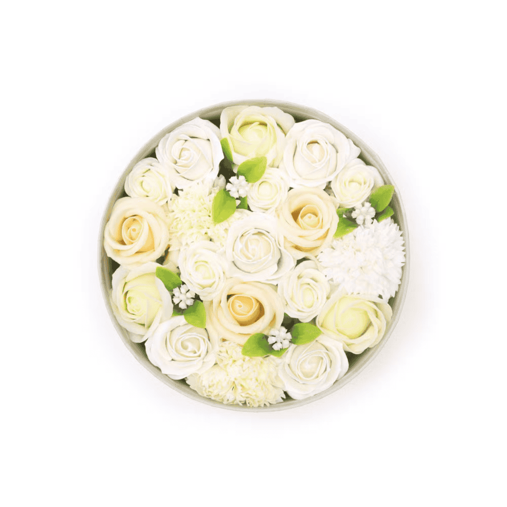 Round arrangement of white and light yellow soap roses with green leaves on a white background