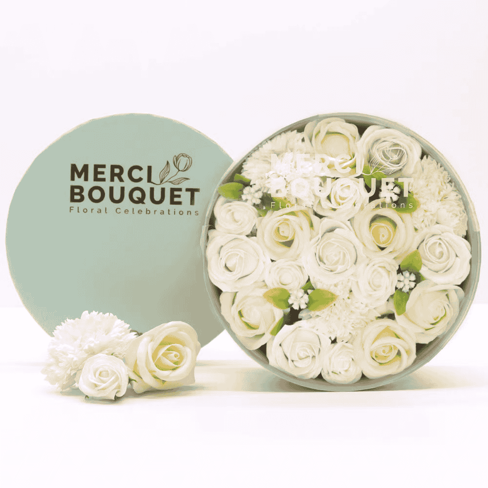 Round box of white soap flowers with 'Merci Bouquet' branding on a light background