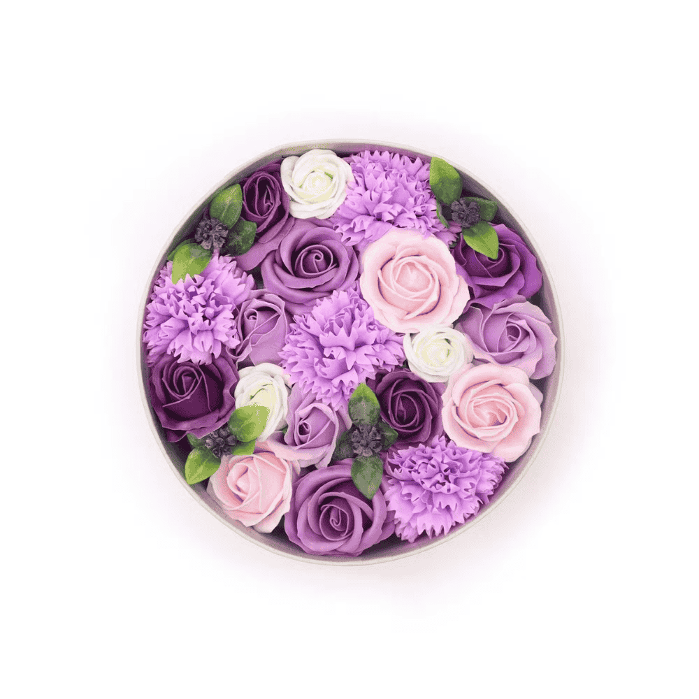 Round arrangement of purple, pink, and white soap flowers in a box on a white background